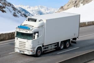 Refrigerated truck driving through a mountain pass for cold-chain transport